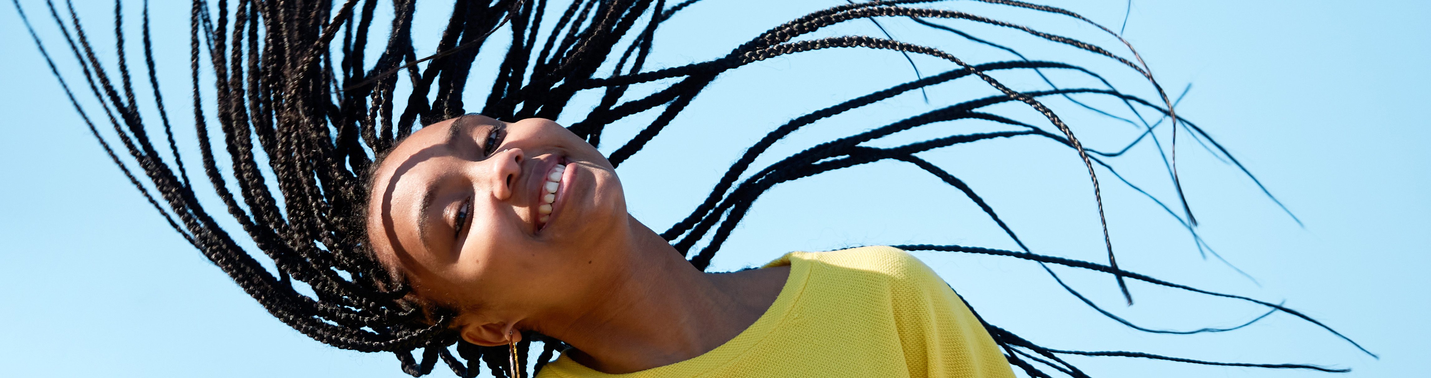 person smiling flipping braids into air